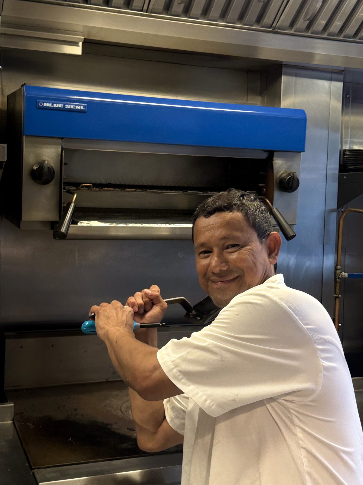 Chef smiling at the grill in a stainless steel commercial kitchen